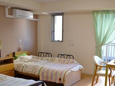 広々として明るい雰囲気。居室には２台のベッドと収納家具などが置かれている。