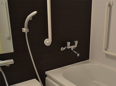 一般的な個浴。黒い壁に白い手すり・シャワー浴槽が設置され、すっきりとした印象。
