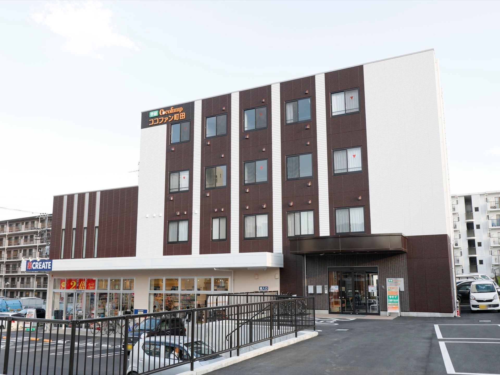 ４階建ての建物。１階部分の多くがガラス張りとなっている。駐車場も広い。