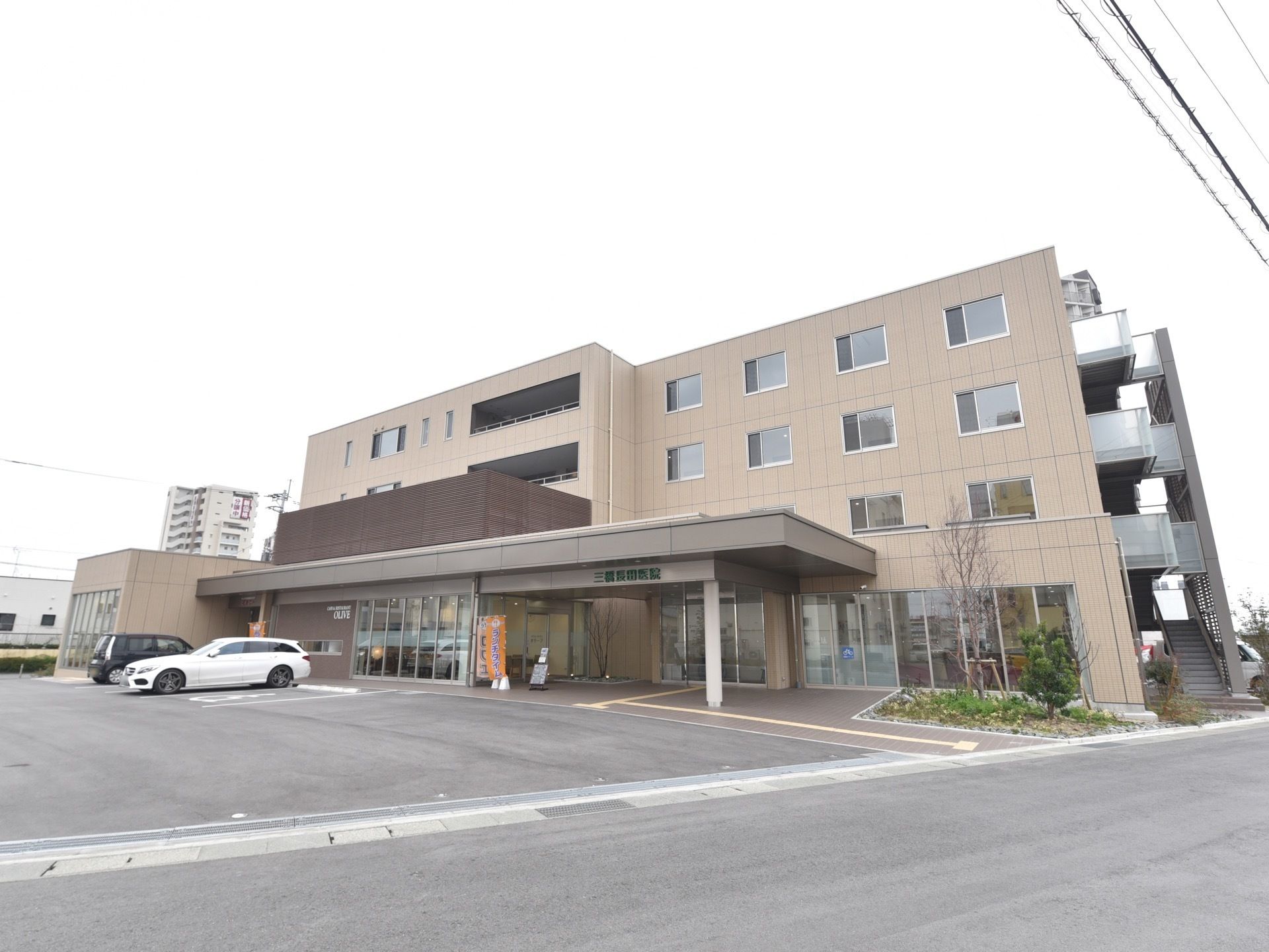 施設は淡いベージュ色と焦げ茶色の配色で、落ち着いた雰囲気となっている。向かって右側には避難階段を設置している。
