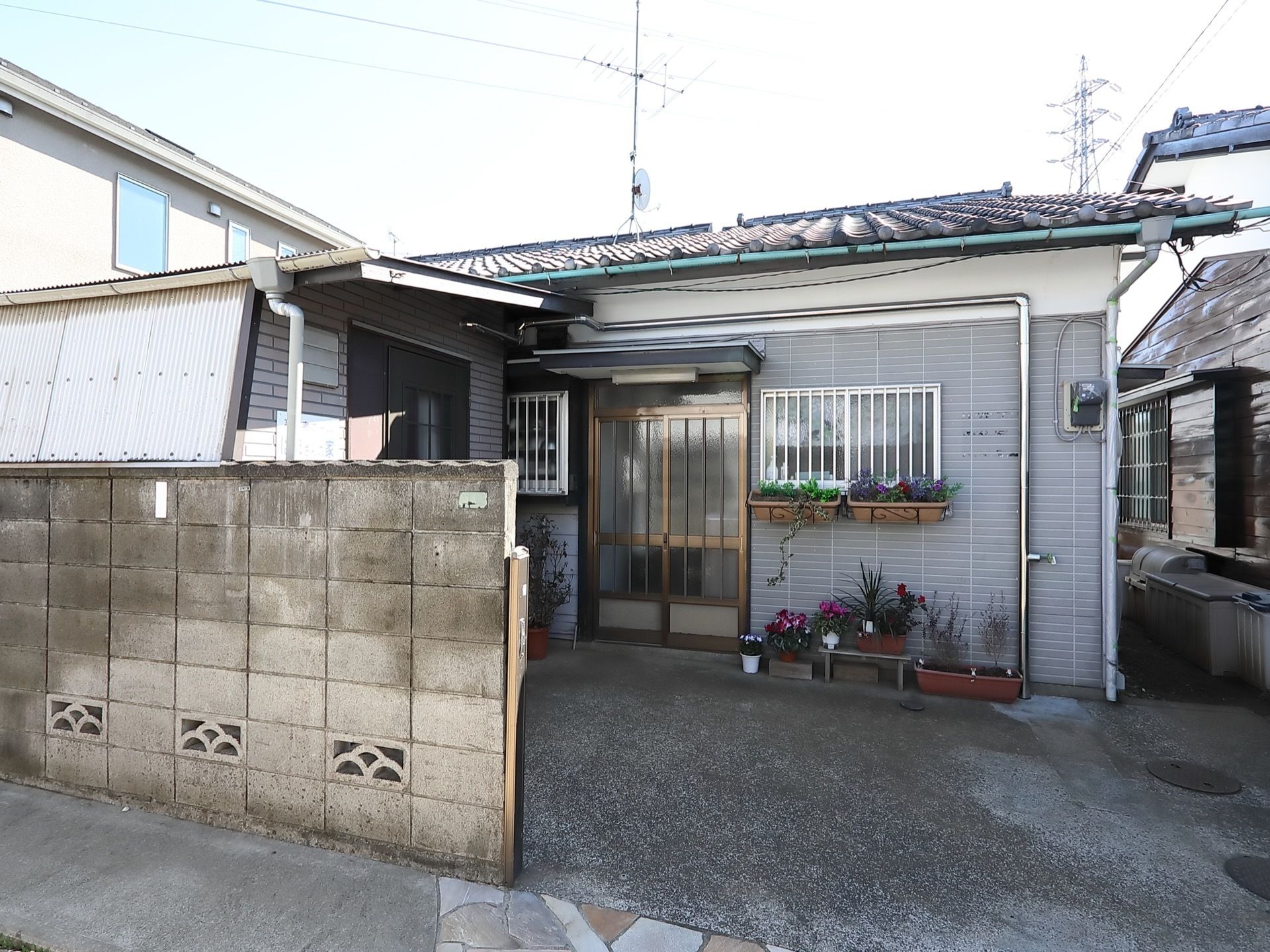 施設と道路はブロック塀で区切られている。玄関のドアはスライド式になっており、ドアの近くに花が飾られている。