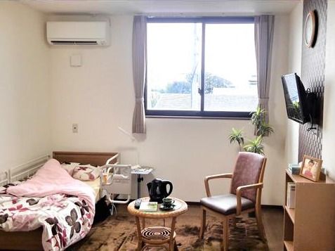 大きな窓が付いた明るい居室にはベッドやテレビなどの家具家電が持ち込まれ、快適な空間となっている。