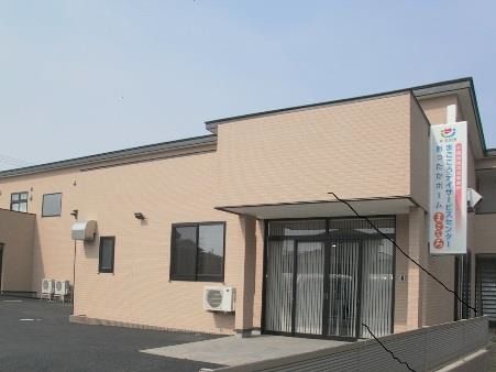 ２階建ての建物はブラウンでまとめられていて、玄関横には白い看板があり、事業所の名前が書かれている。