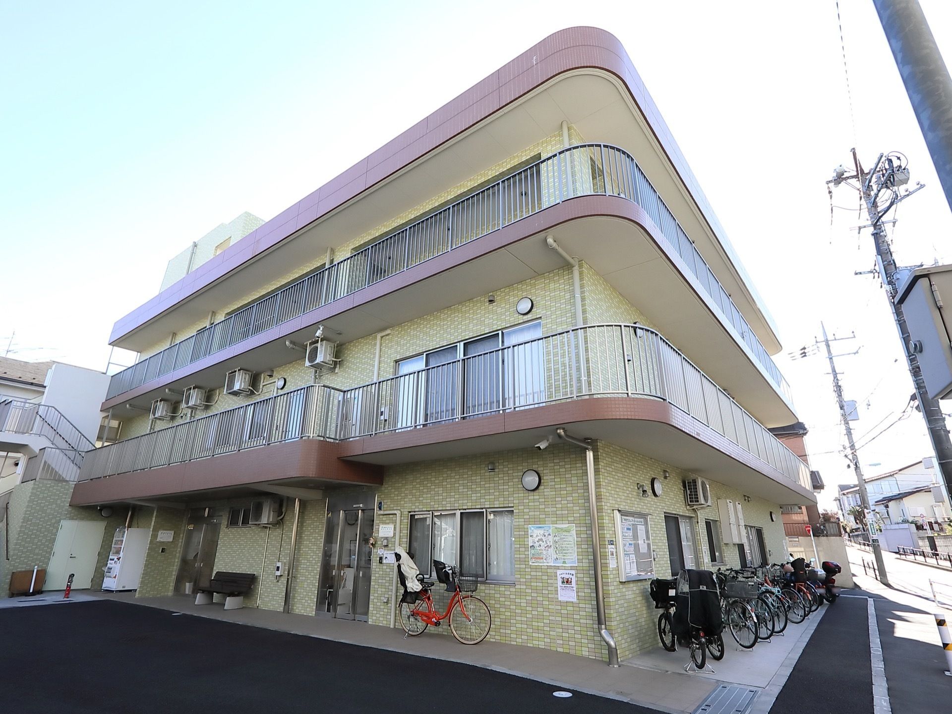 ３階建てのモザイクタイルの外壁の建物で、2、3階の周りは手すりに囲まれている。敷地内は舗装されている。