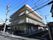 丸みを帯びた可愛らしい外観の建物である。敷地内には駐輪スペースが設けられており、バイクや自転車が停められている。