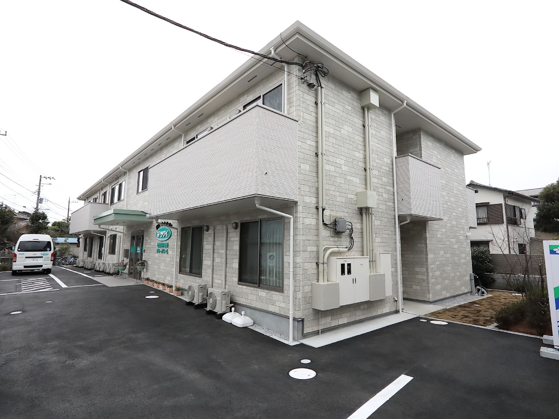 2階建てのアットホームな雰囲気の建物。玄関には屋根が付き、扉のすぐ横にホームの名前が書かれている。
