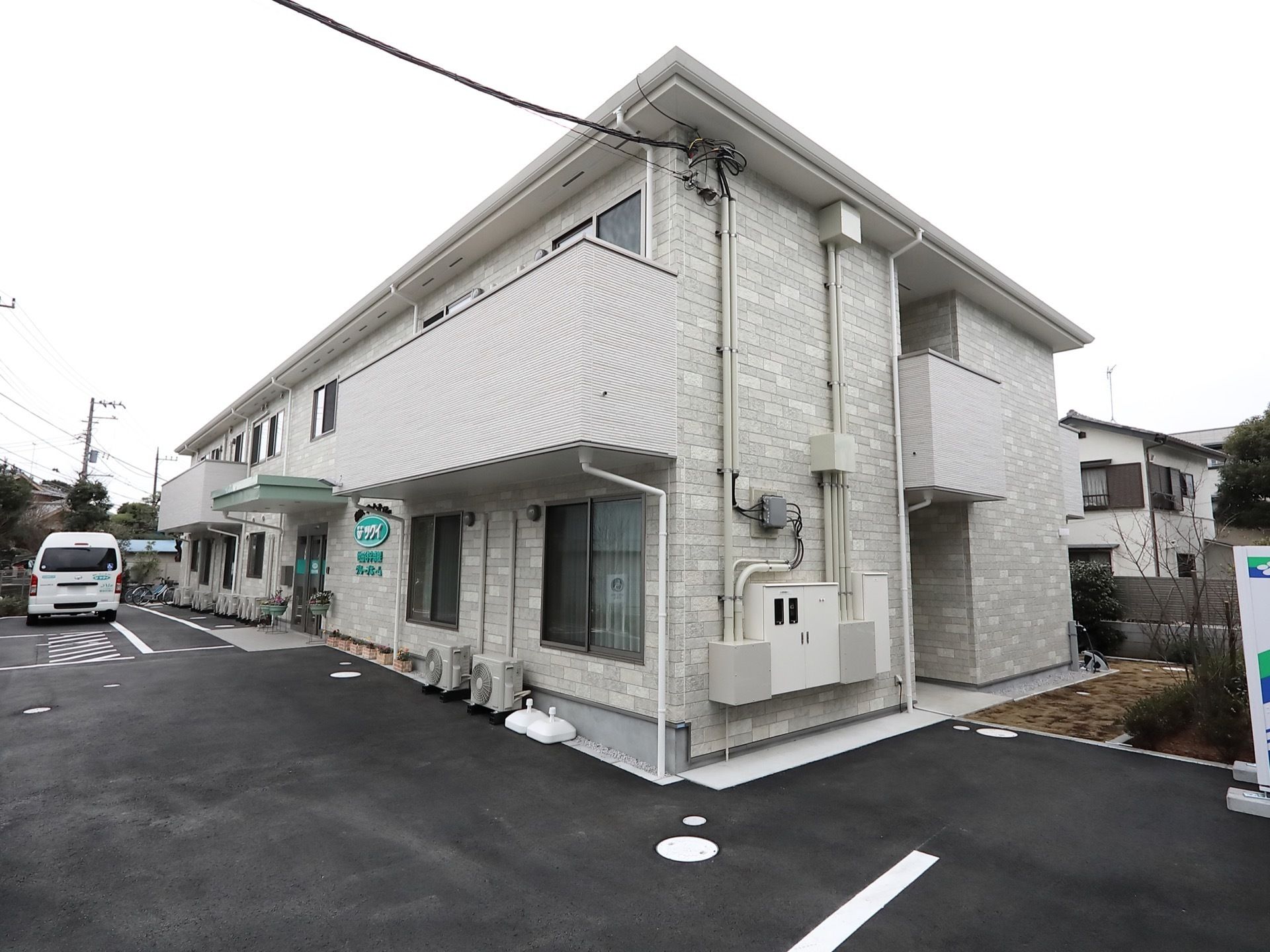外観が２階建てアパートのような施設である。バルコニーが２階の居室部分に設置されている。建物前に駐車スペースが設けられている。