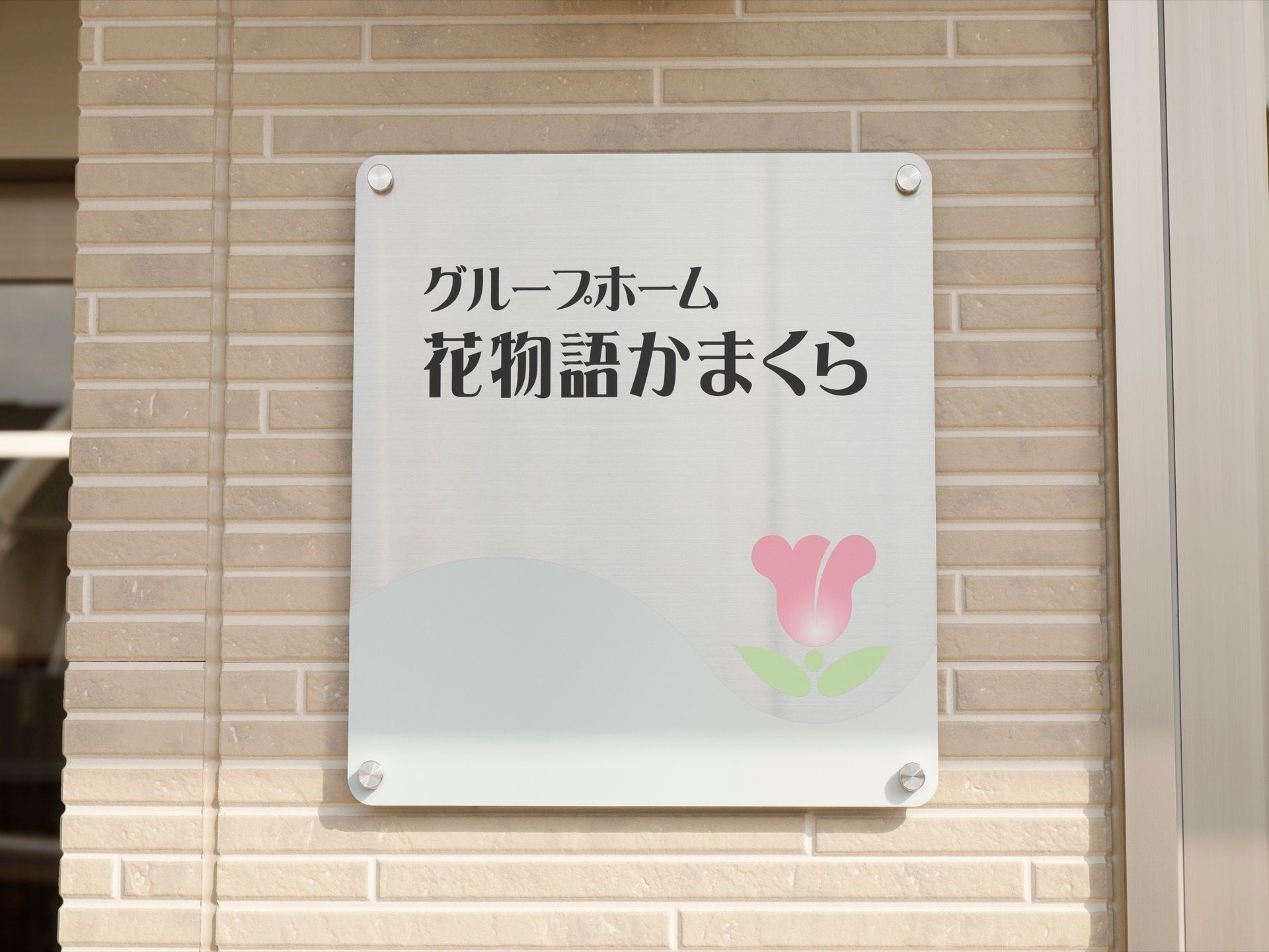 エントランスの壁に施設名の書かれた看板が掲げられている。チューリップのイラストが愛らしいく、施設内の雰囲気が想像できる。