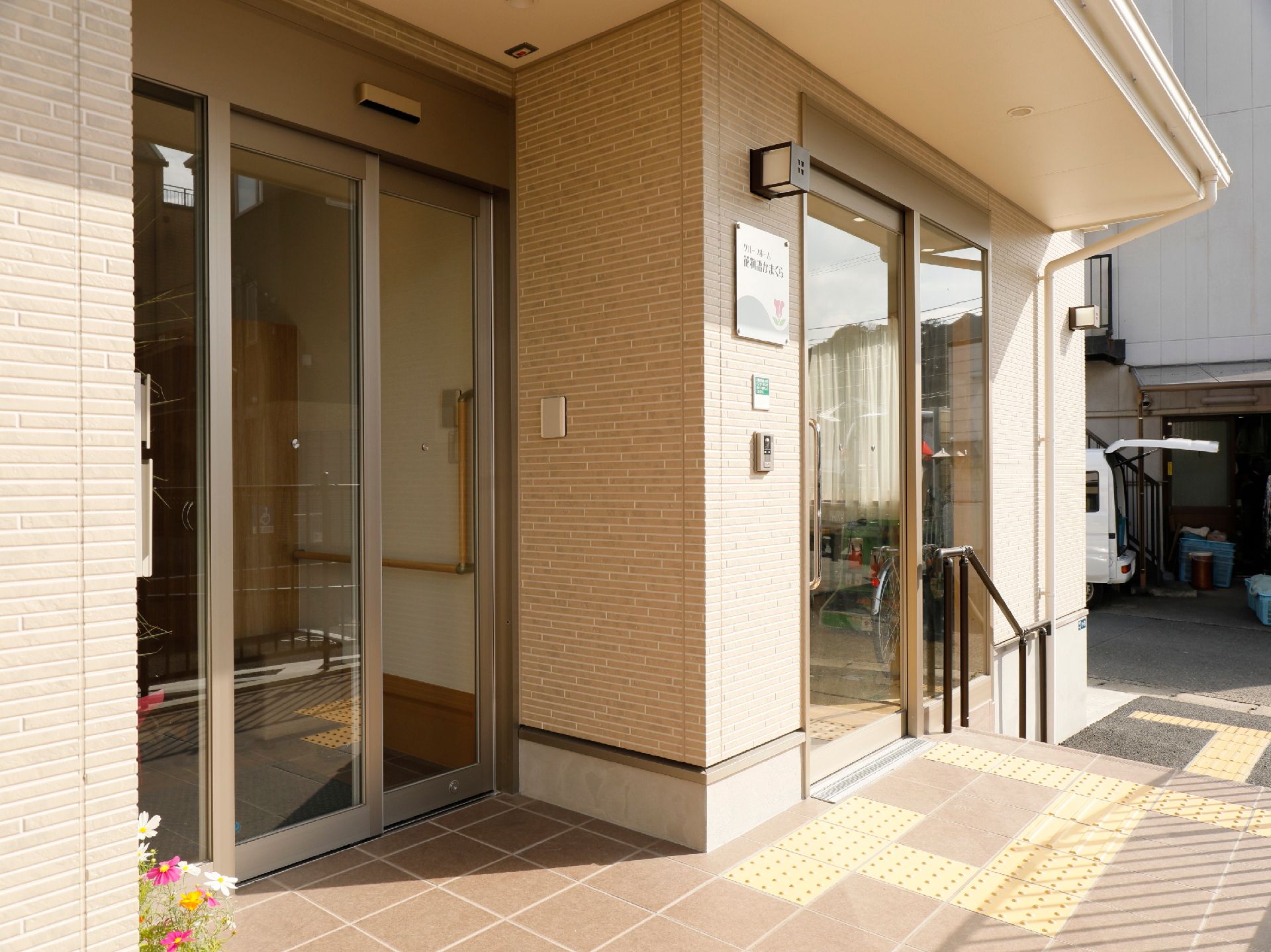 ブラウン系の建物。２階建てで一般の住宅に近い造り。芝生スペースもある。