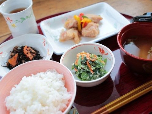 トレイの上には白いご飯やみそ汁、メインのとり肉料理に小鉢に盛られたひじきと青菜の和え物、そしてお茶がある。