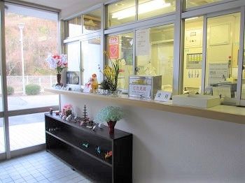 フロントはガラス張りで中がよく見える。ご意見箱や受付と書かれた札が置かれ、花や小物が飾られている。