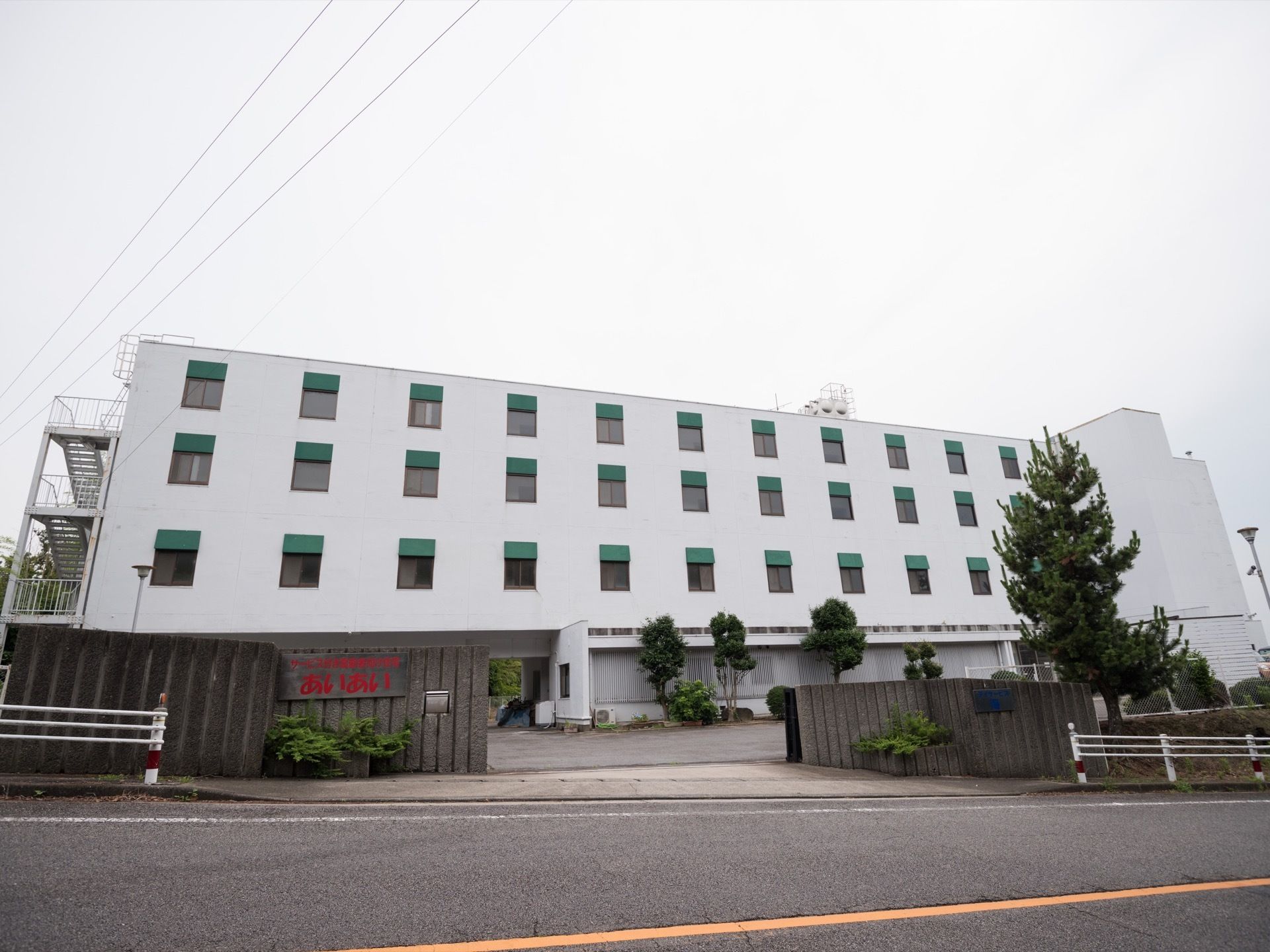 施設は企業のビルのように重厚な雰囲気の外観になっている。広い敷地に４階建ての建物があり、外階段が取り付けてある。
