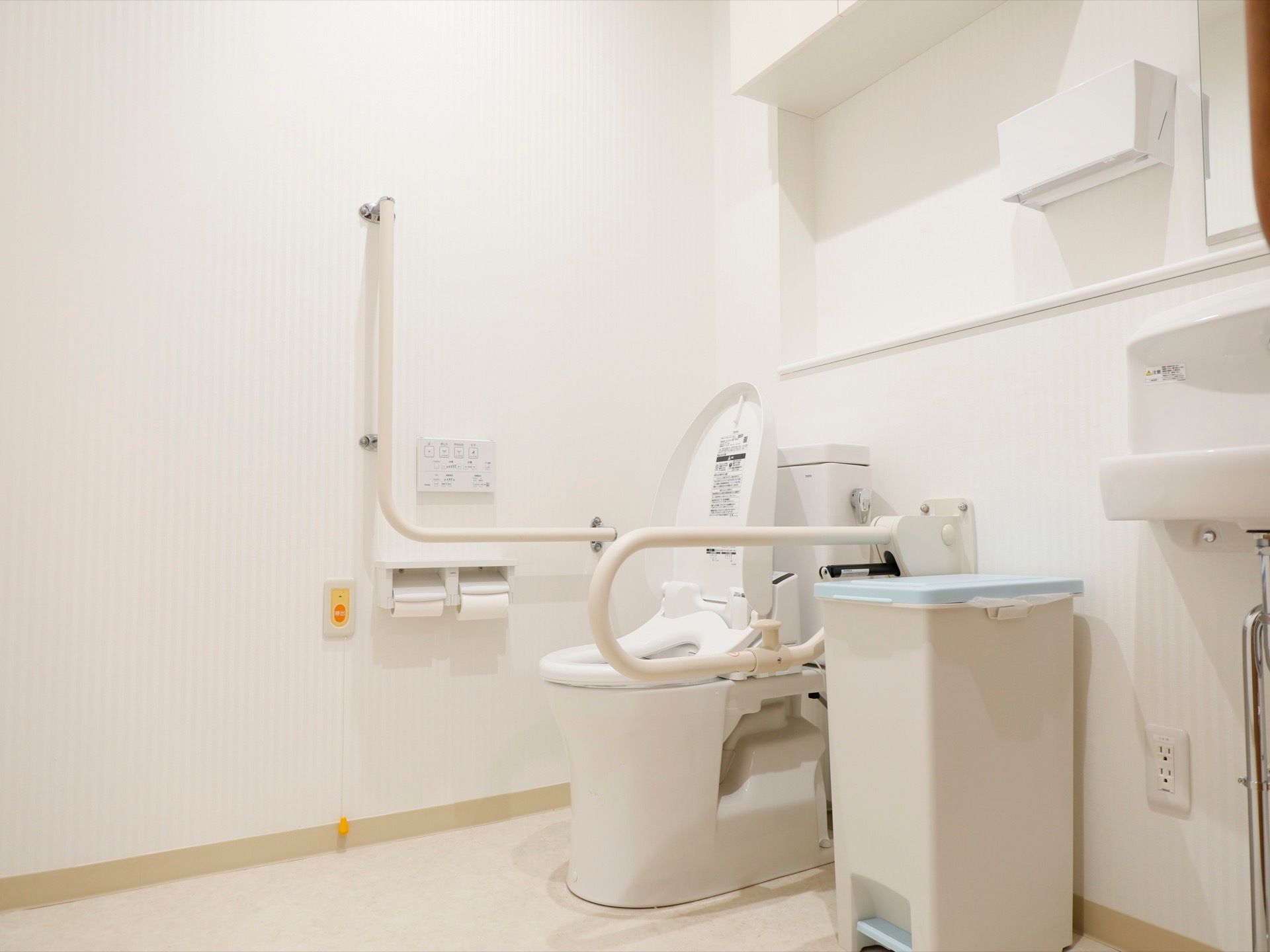 トイレは白を基調にしており、明るく清潔感がある。便座の両側に手すり、壁に緊急ボタンを設置して安全面にも配慮している。