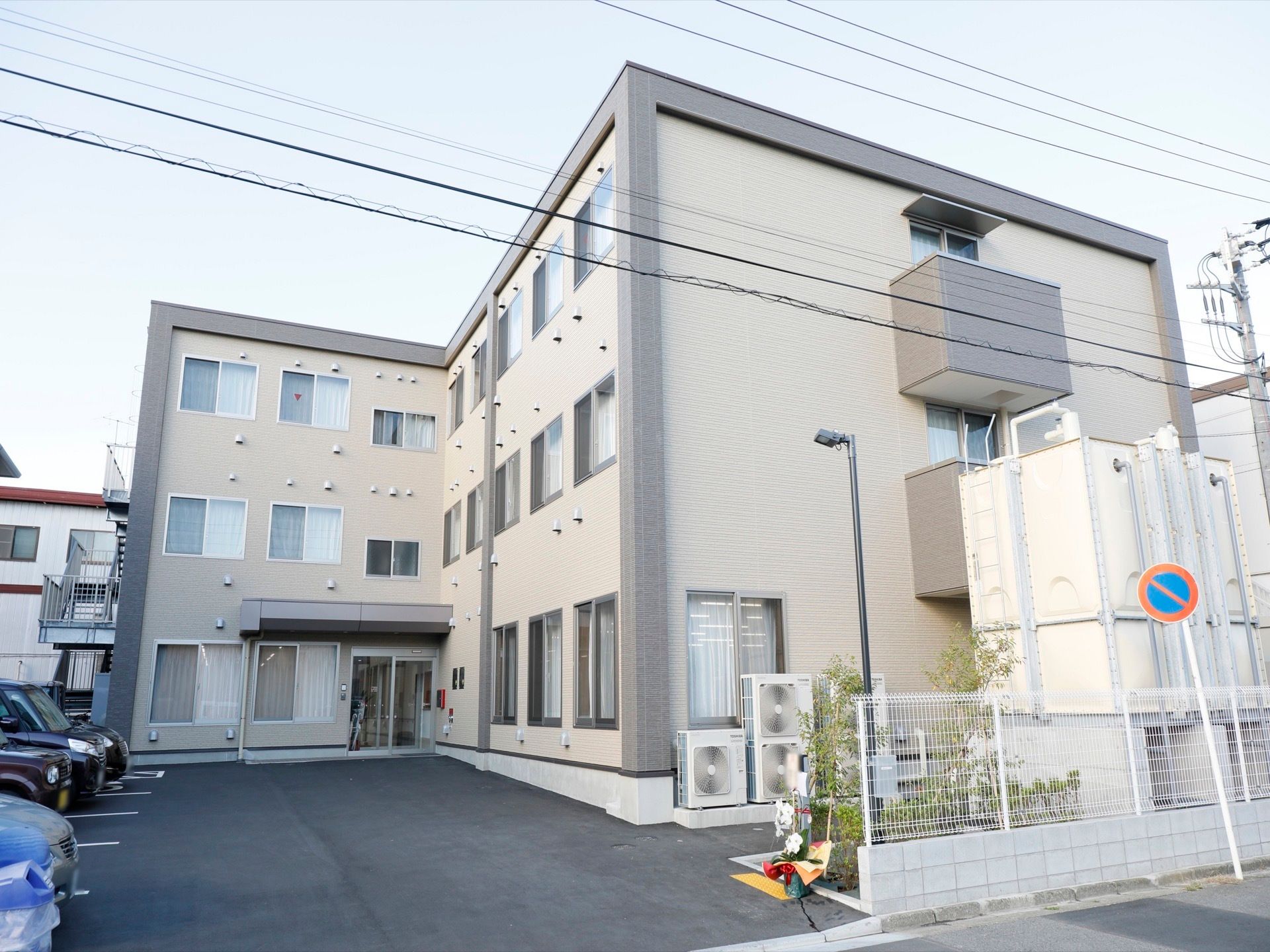 外観はアイボリーで、地上3階建ての建物となっている。敷地には駐車スペースが完備されているので、車で来訪することができる。