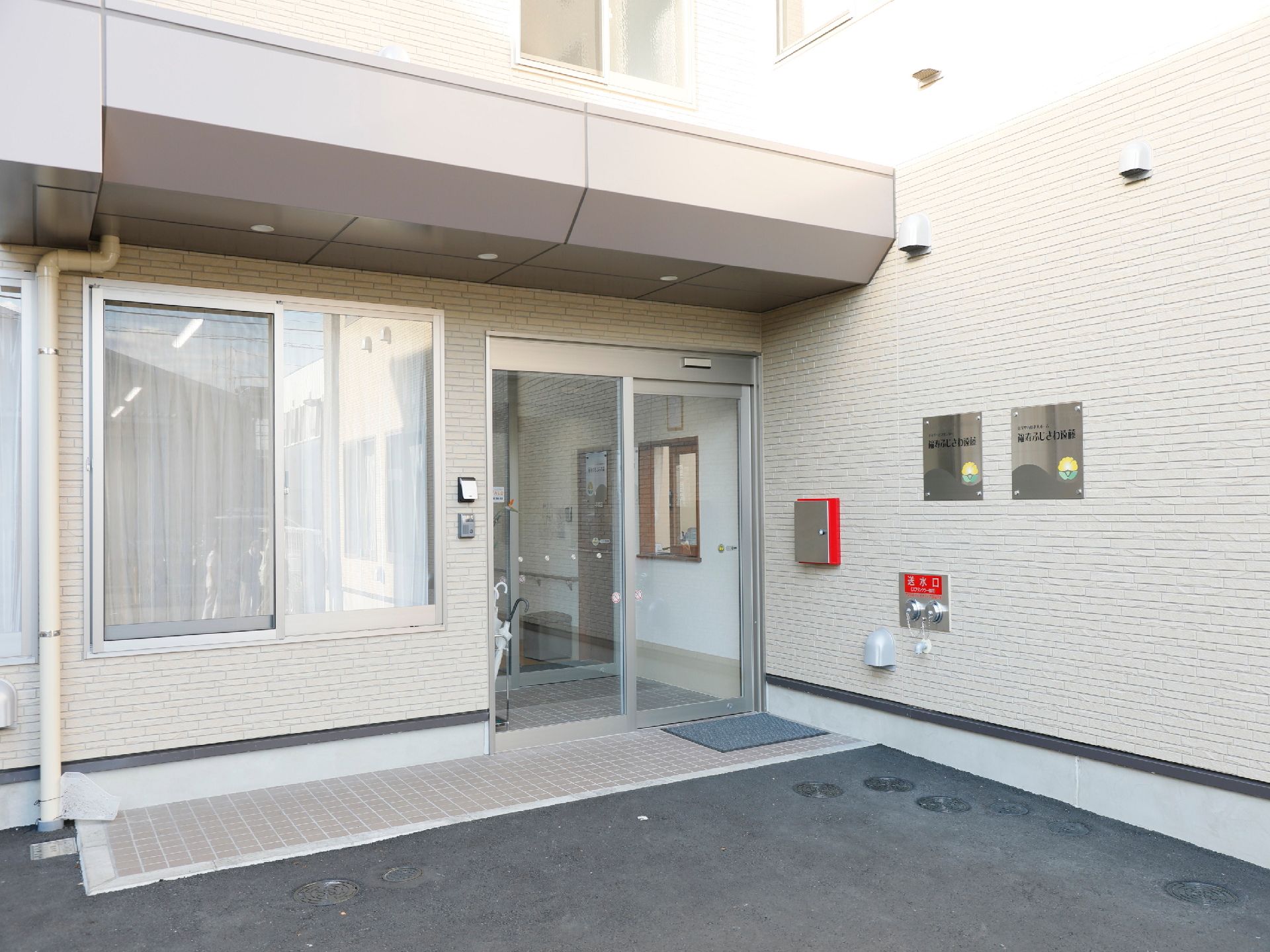 広い駐車スペースのある３階建てのホーム。エル字型で玄関の上には屋根やついている。