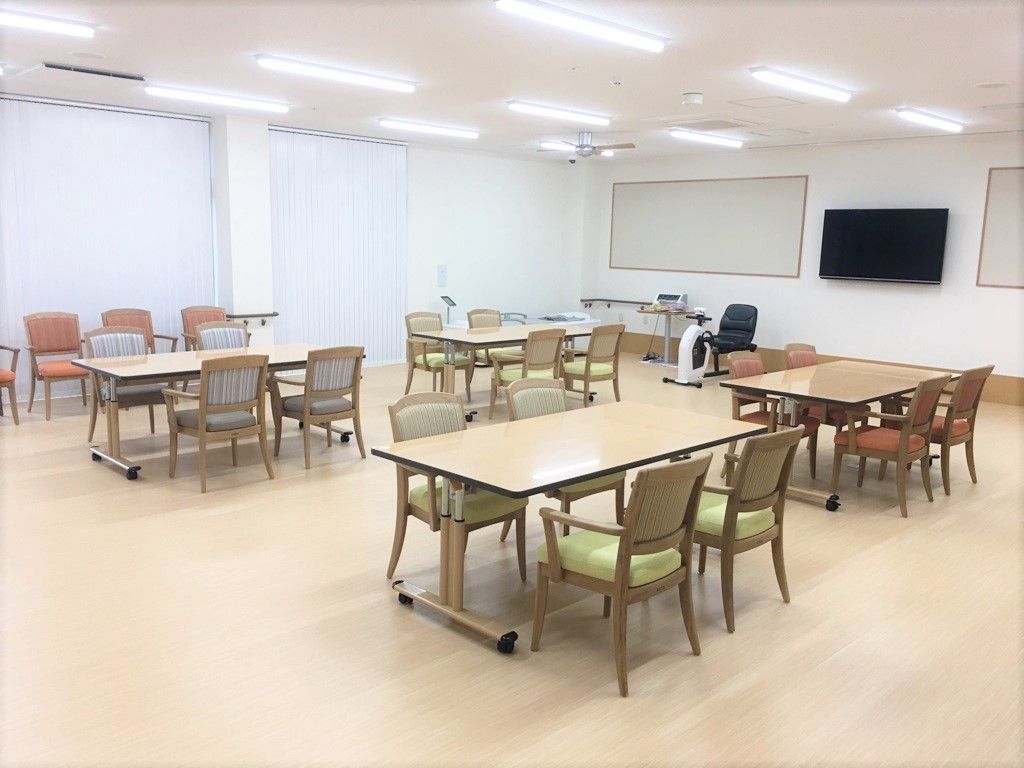 木製の机に椅子が4脚ずつ置かれている。椅子はオレンジや黄緑色など、色とりどりである