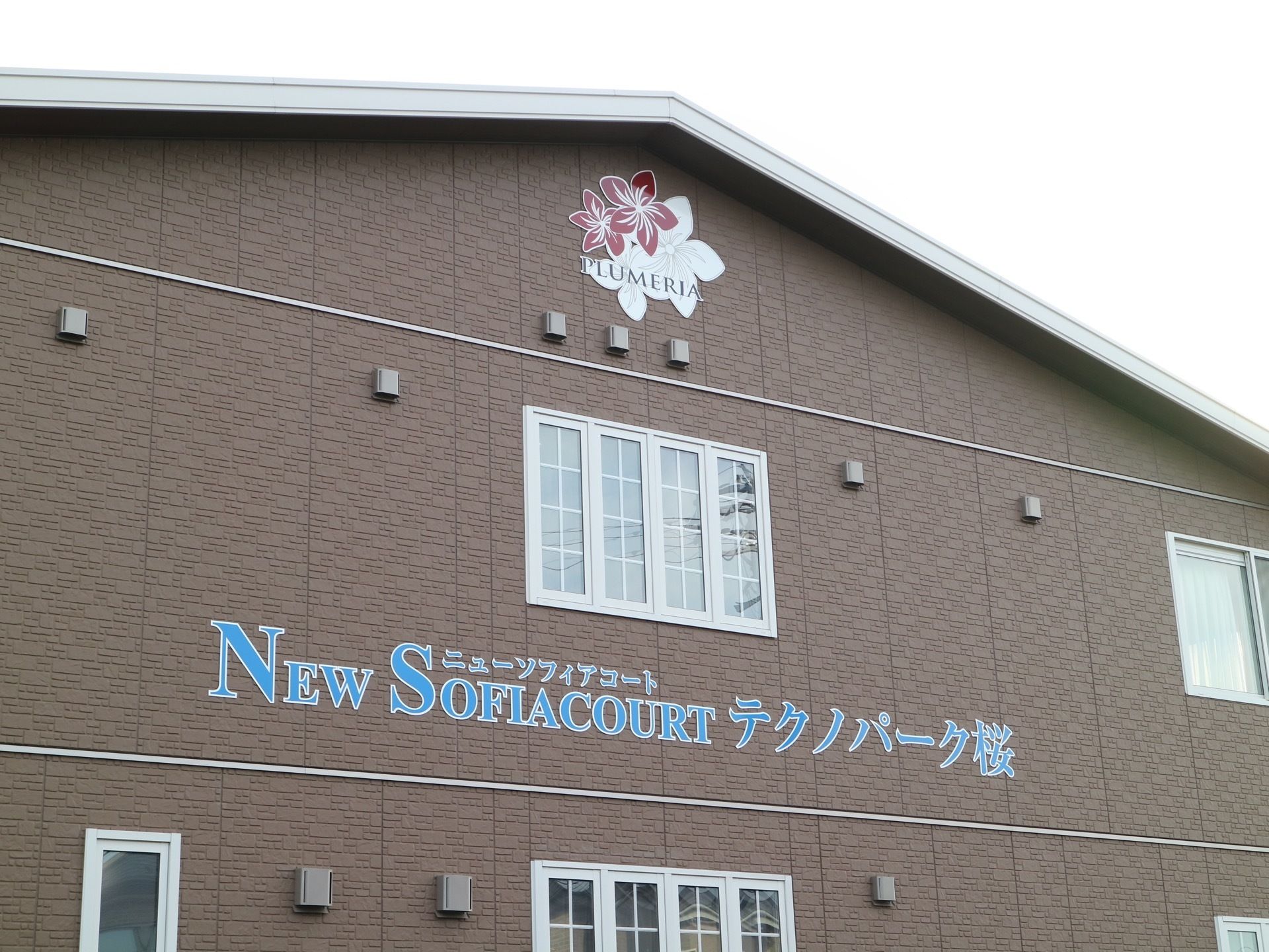 茶色のレンガ調の外壁の施設である。三角の屋根が乗っており、屋根の下の壁には施設名とロゴが描かれている。
