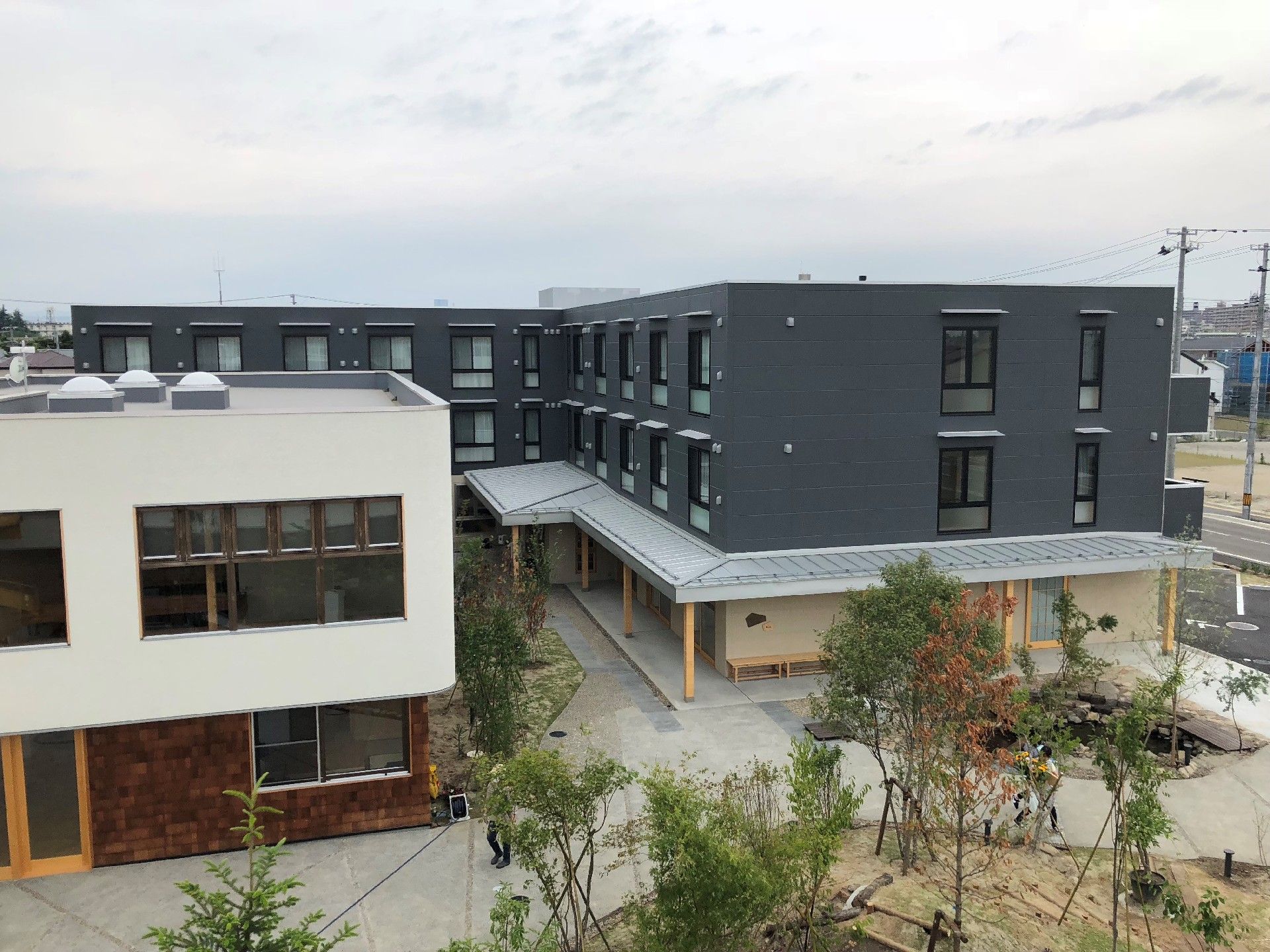 3階建てのどっしりとしたエル字型の建物のすぐ横には介護事業所がある。
