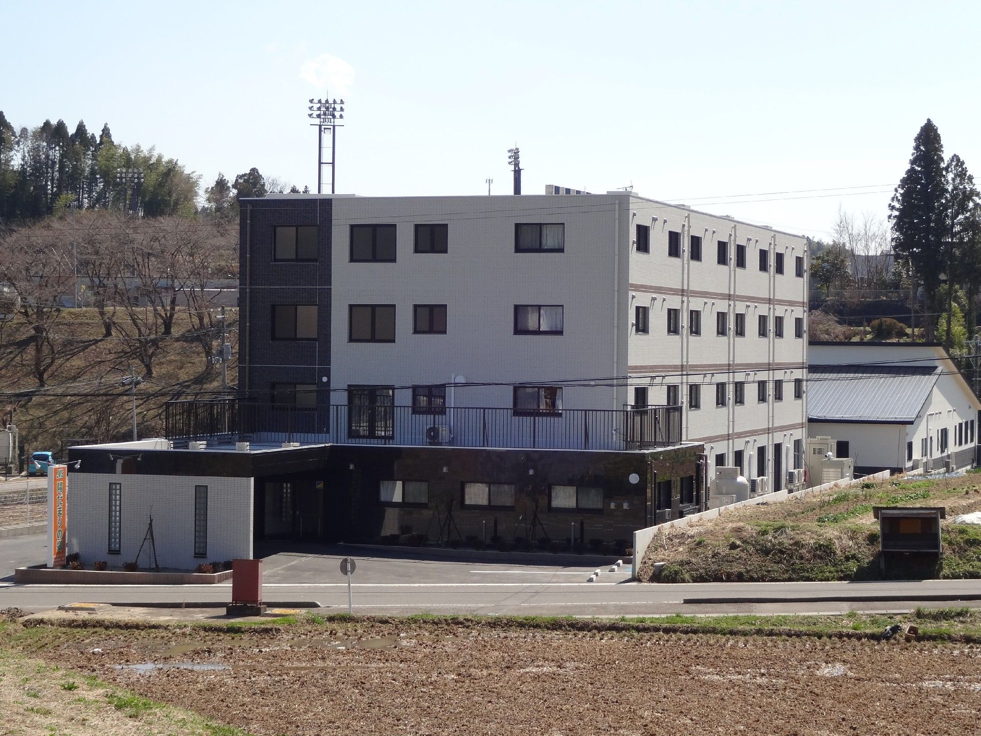 壁が白と茶色に分かれている4階建ての建物