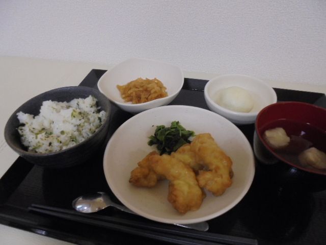 トレイの上には白いご飯やみそ汁、メインの揚げ物料理に小鉢に盛られた野菜などがある。