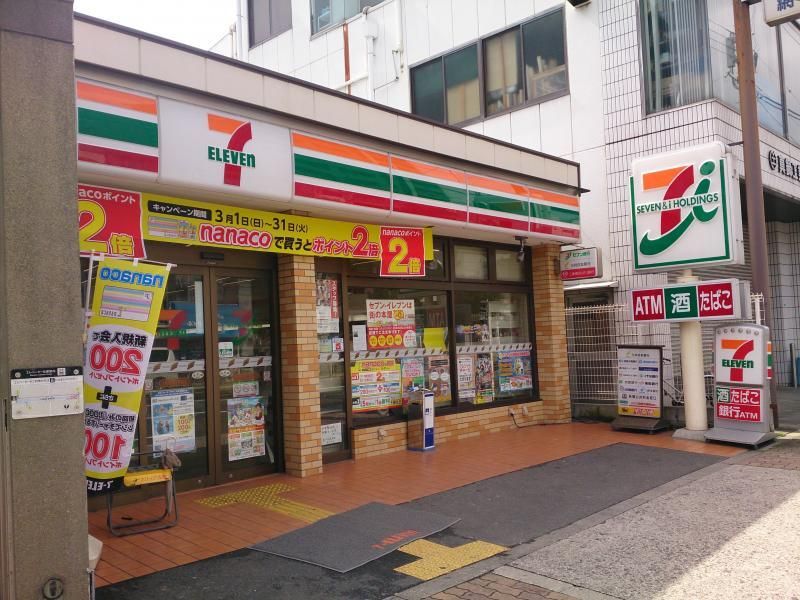 セブンイレブン 大阪新深江駅南店の外観。建物の前には点字ブロックや駐車スペースがある。
