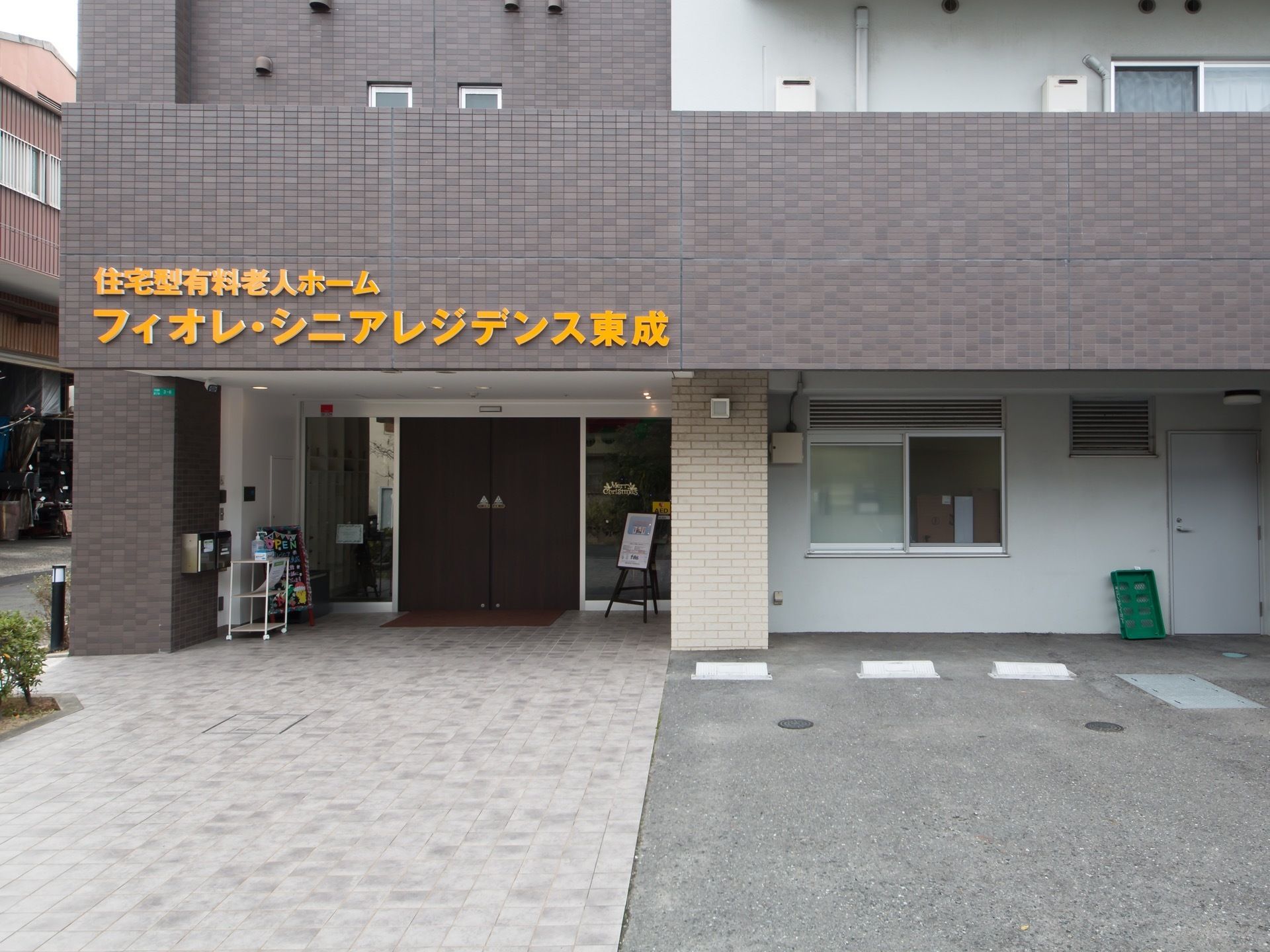 ダークグレーのレンガ張りの外観の建物である。入口はガラス扉で、開け放たれている。壁にオレンジの文字で施設名が表示されている。