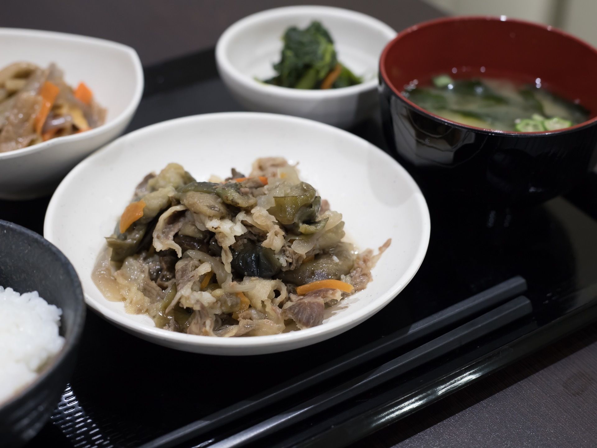 黒いトレイに食事が並べられている。白米と味噌汁、おひたしの入った小鉢があり、メインは牛肉の和え物である。