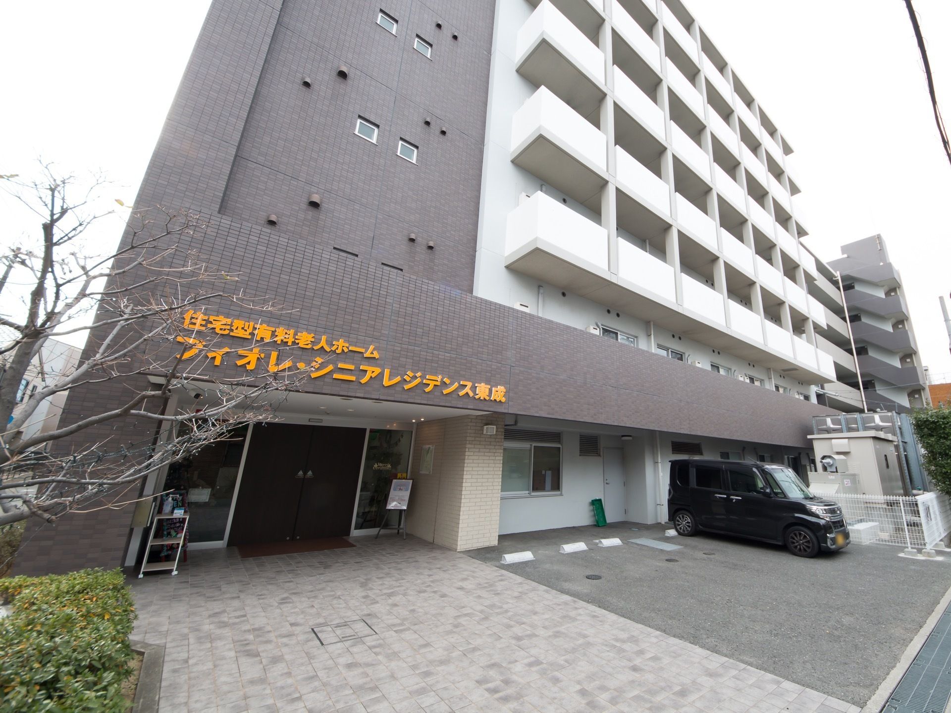 ７階建ての大型マンションのような造りで、ダークグレーと白の２色に塗り分けられている。入口横に駐車スペースがある。