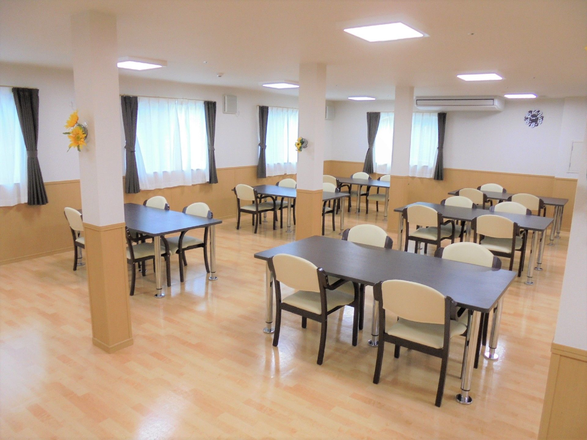 木製のダイニングテーブルにはいすがセットされ、窓から日差しが降り注ぐ明るい食堂。