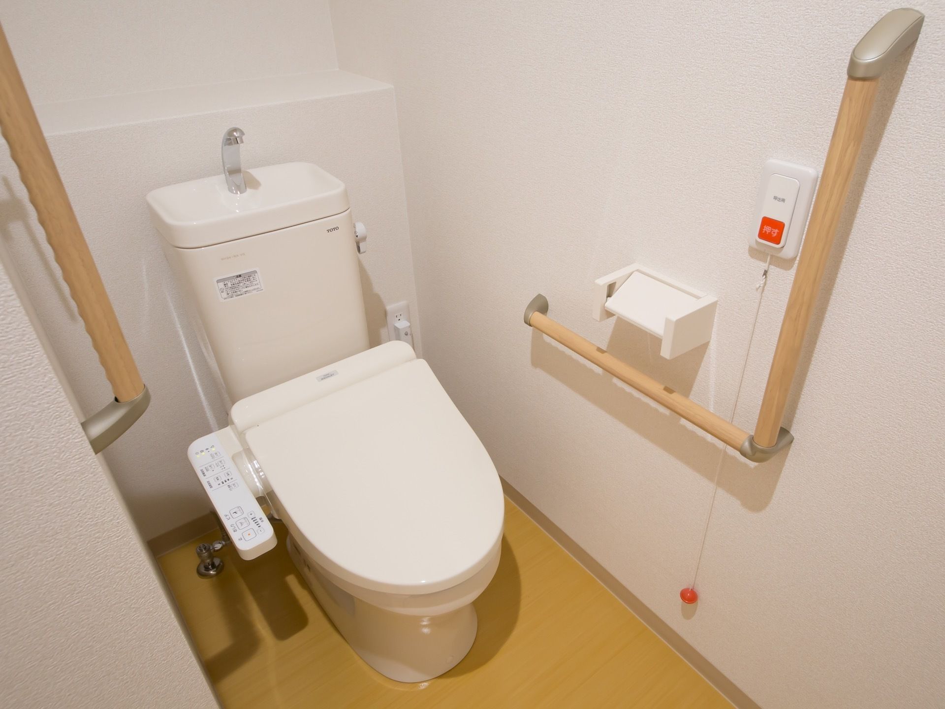 トイレは、清潔感のある白を基調とした空間内に設置されている。また、温水洗浄機能もあり、壁には非常用ベルも取りつけられている。