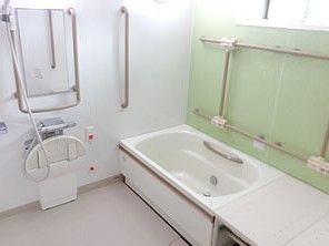 白い浴槽が置かれた広い浴室は洗い場がゆったりとしていて、シャワーや手すりも設置されている。