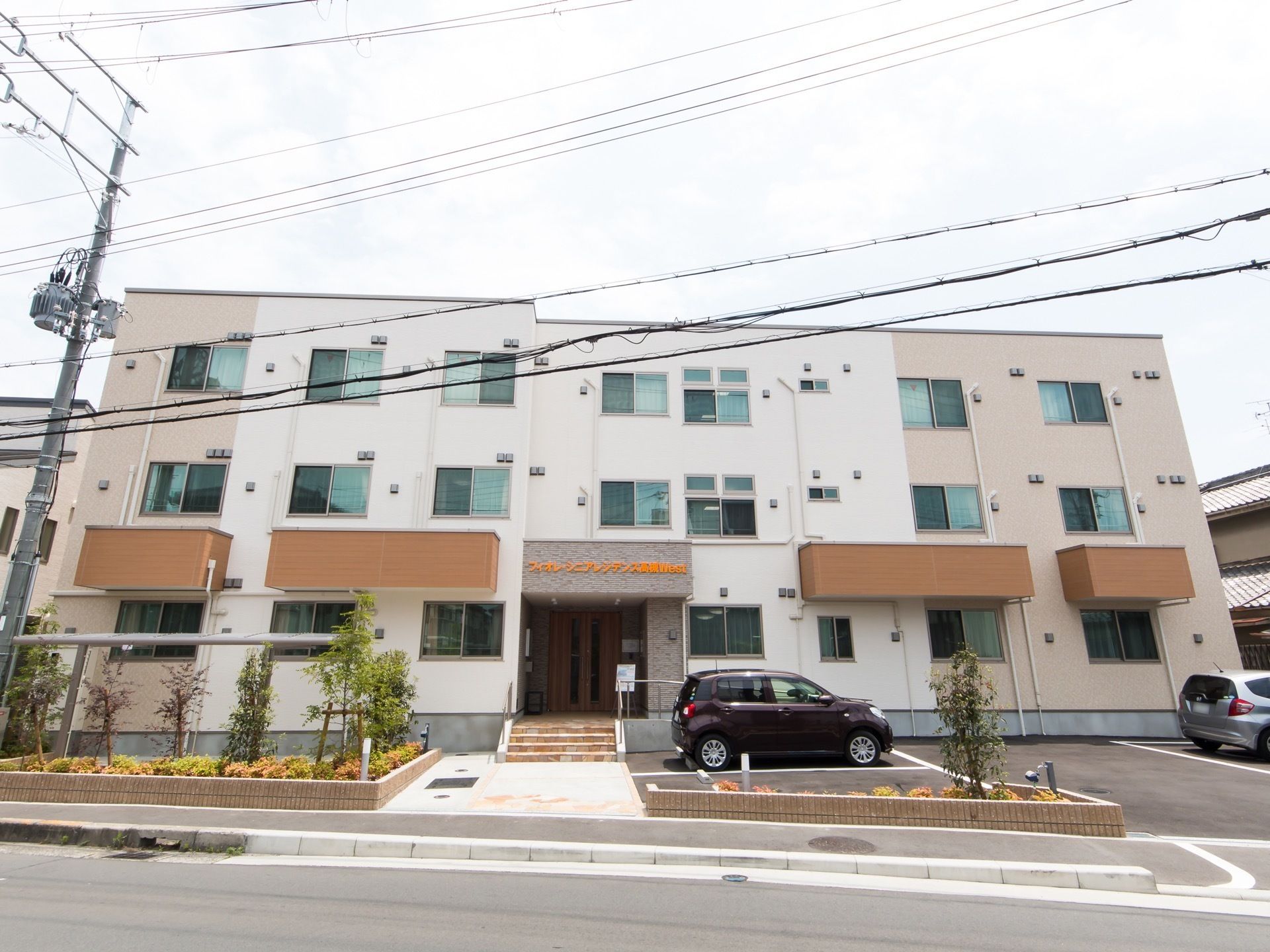 建物が３階建て構造をしているのが外見からわかる。正面玄関はそのほぼ真ん中に位置しており、階段とスロープを備えている。