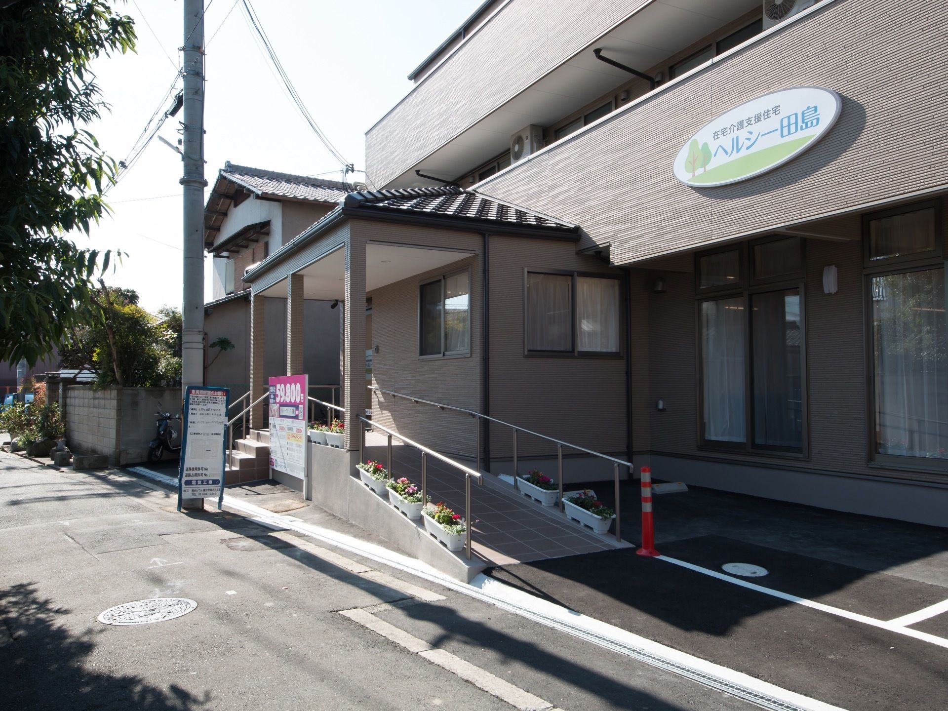 施設の玄関までは手すり付きのスロープが設置されている。色とりどりの花を植えたプランターが置かれており、華やかである。