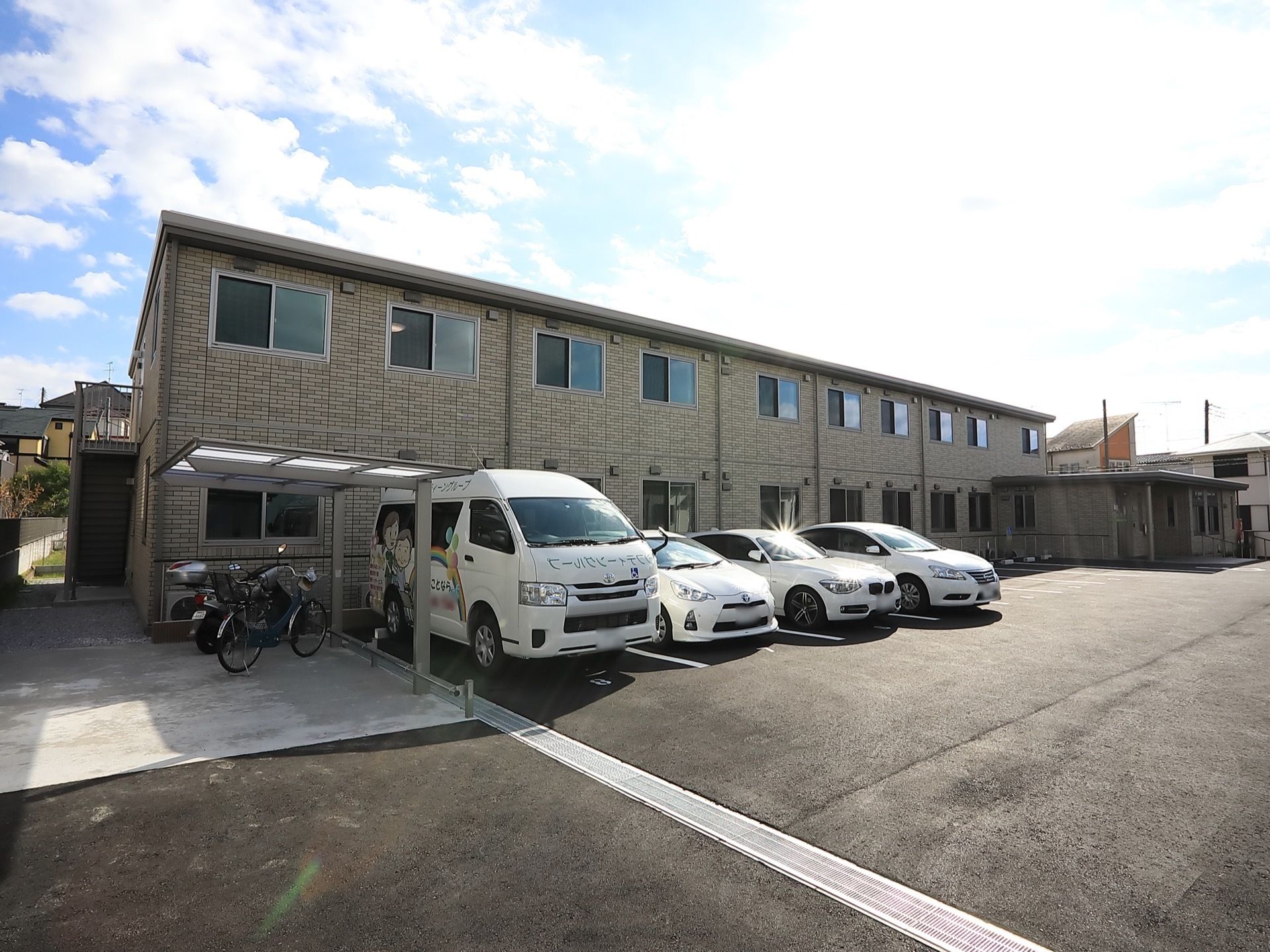 施設の周囲には高い建物がなく、日当たりがとてもよい。駐車場のすぐ横には、ひさしがついた駐輪スペースがある。