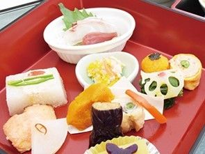 赤い器に盛られたお祝い膳。一口サイズのきれいな料理が並んでいる。