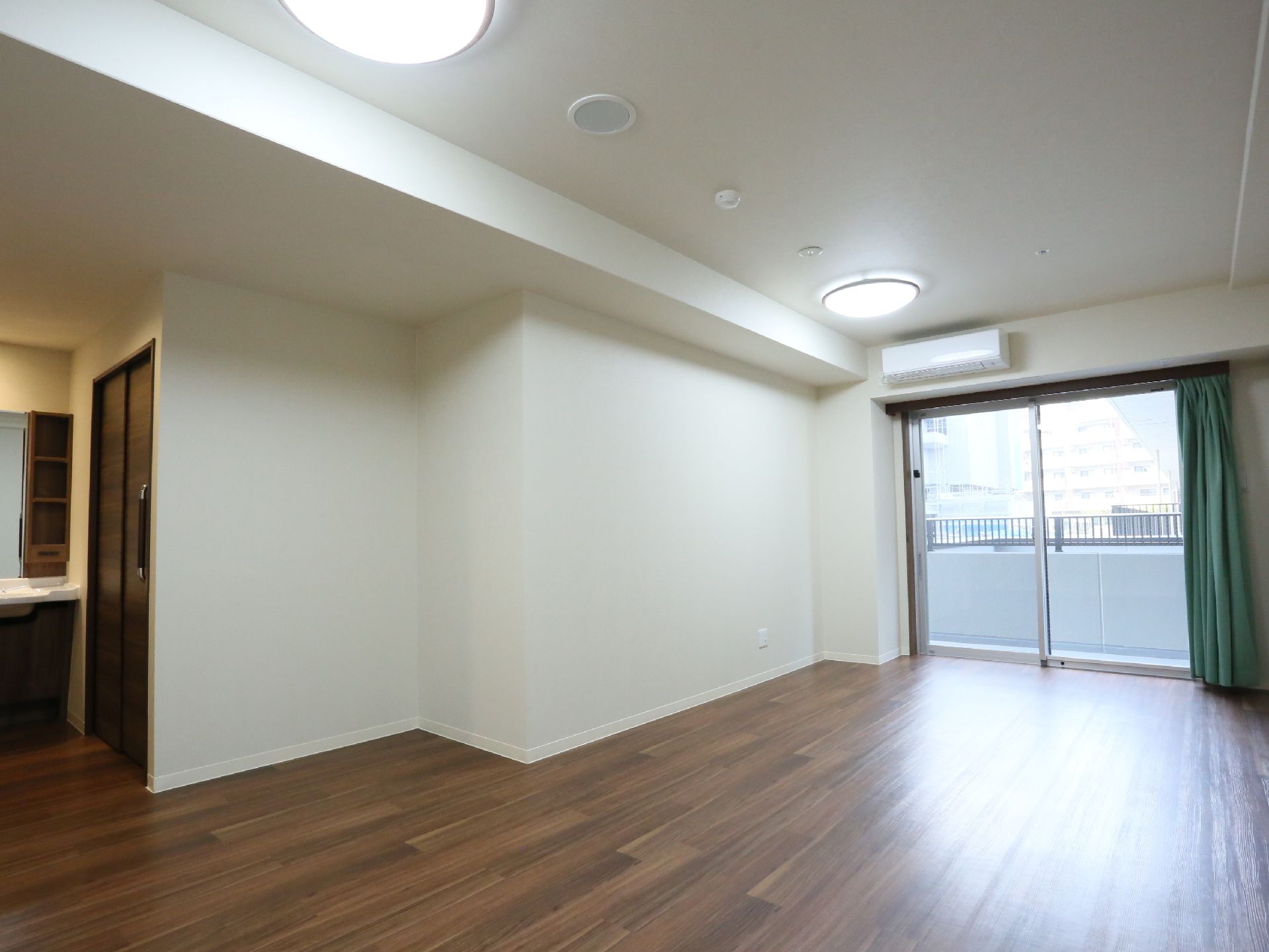 広い居室は床がフローリングになっており、壁は白色になっている。また部屋にはエアコンと大きな窓が完備されている。