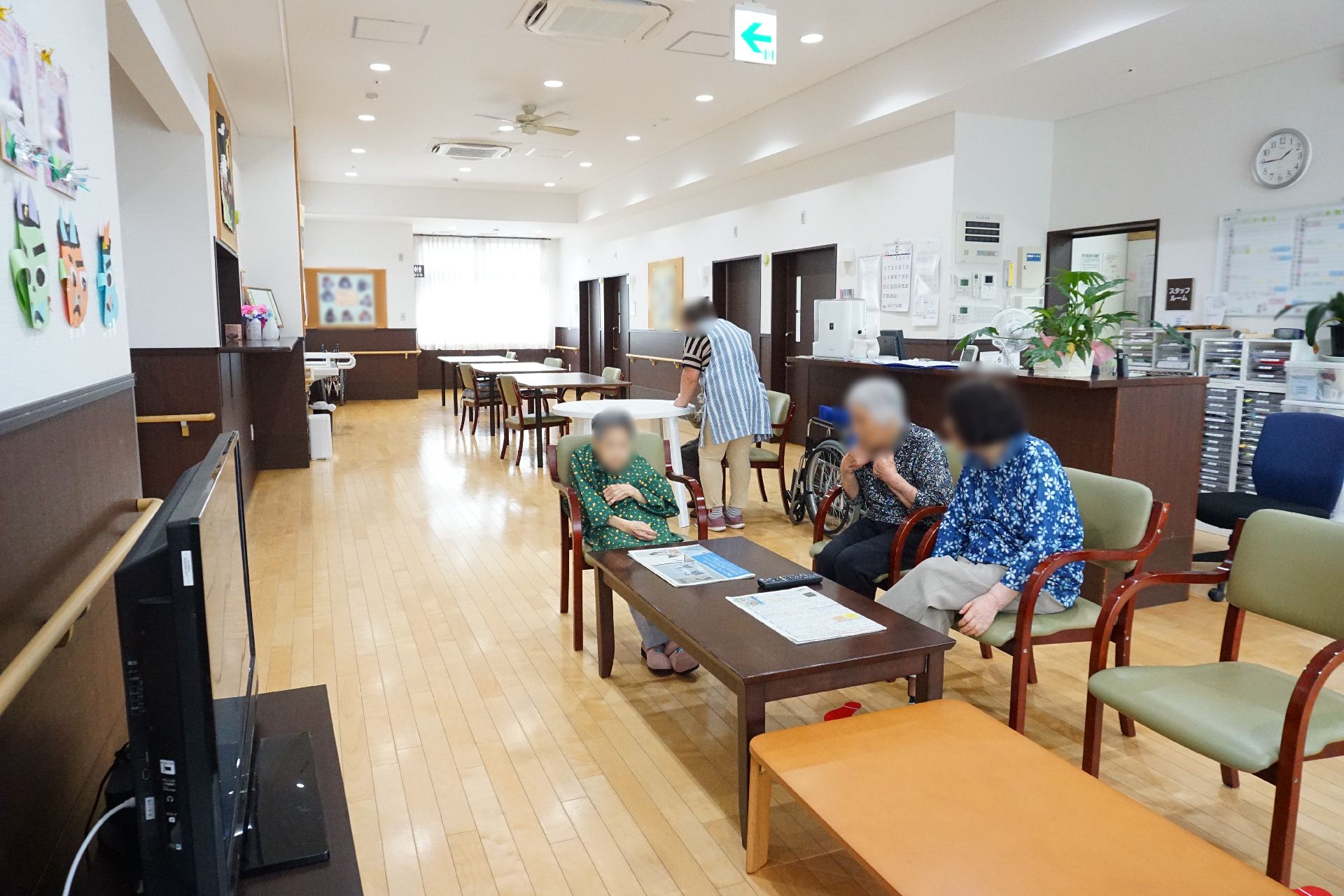 長いテーブルが並べられ、入居者が思い思いの時間を過ごしているリビング