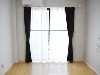 エアコンや緊急通報装置が設置されたフローリングの居室。日当たりがよく清潔感がある。