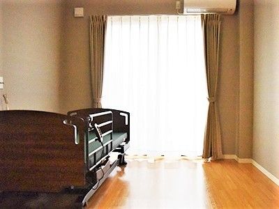 介護用ベッドのわきには緊急通報装置が設置され、壁にはエアコンもある。