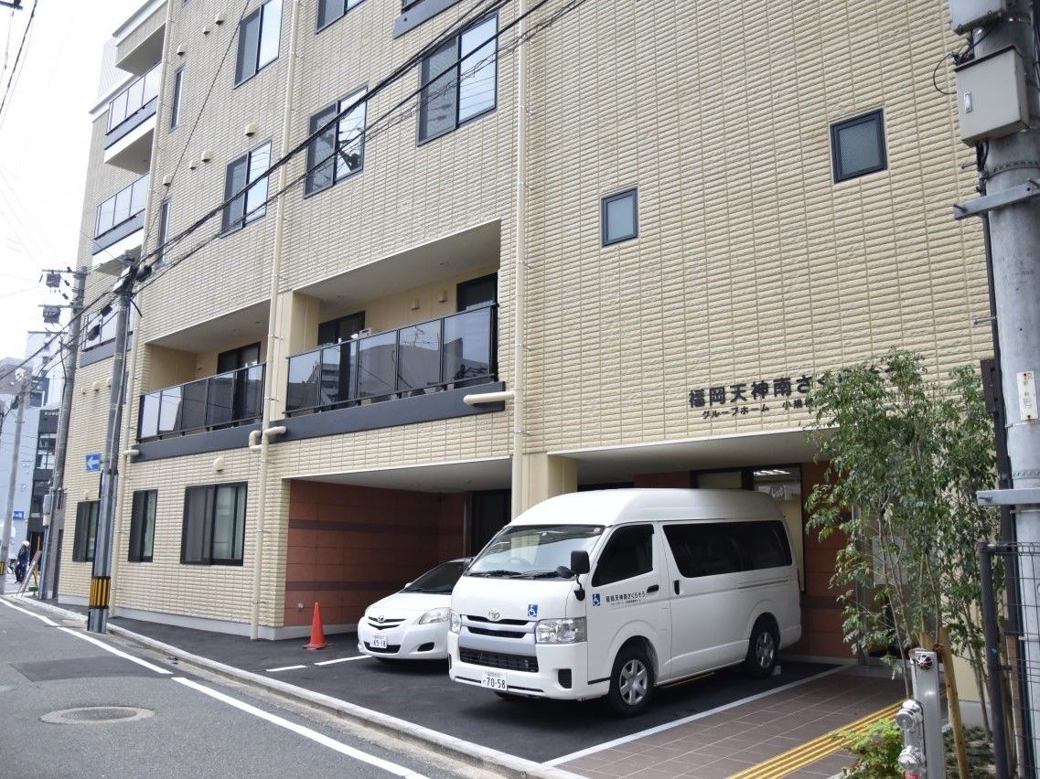 ５階建ての建物。ベージュで２階にはベランダが付き、１階部分が一部駐車場になっている。