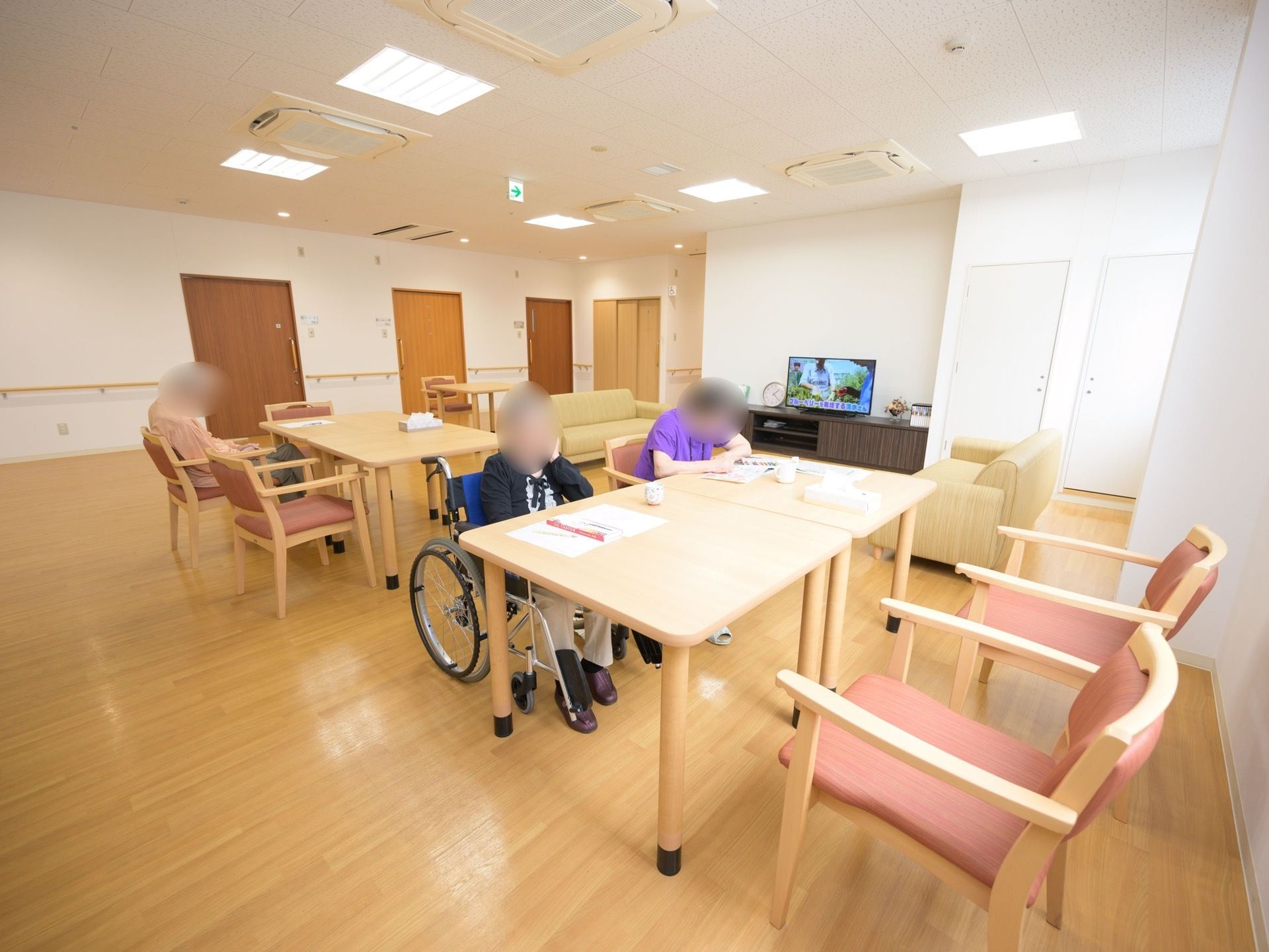 明るく開放的な共有スペースでは、入居者様が思い思いに過ごしている。テレビやソファーを用意。