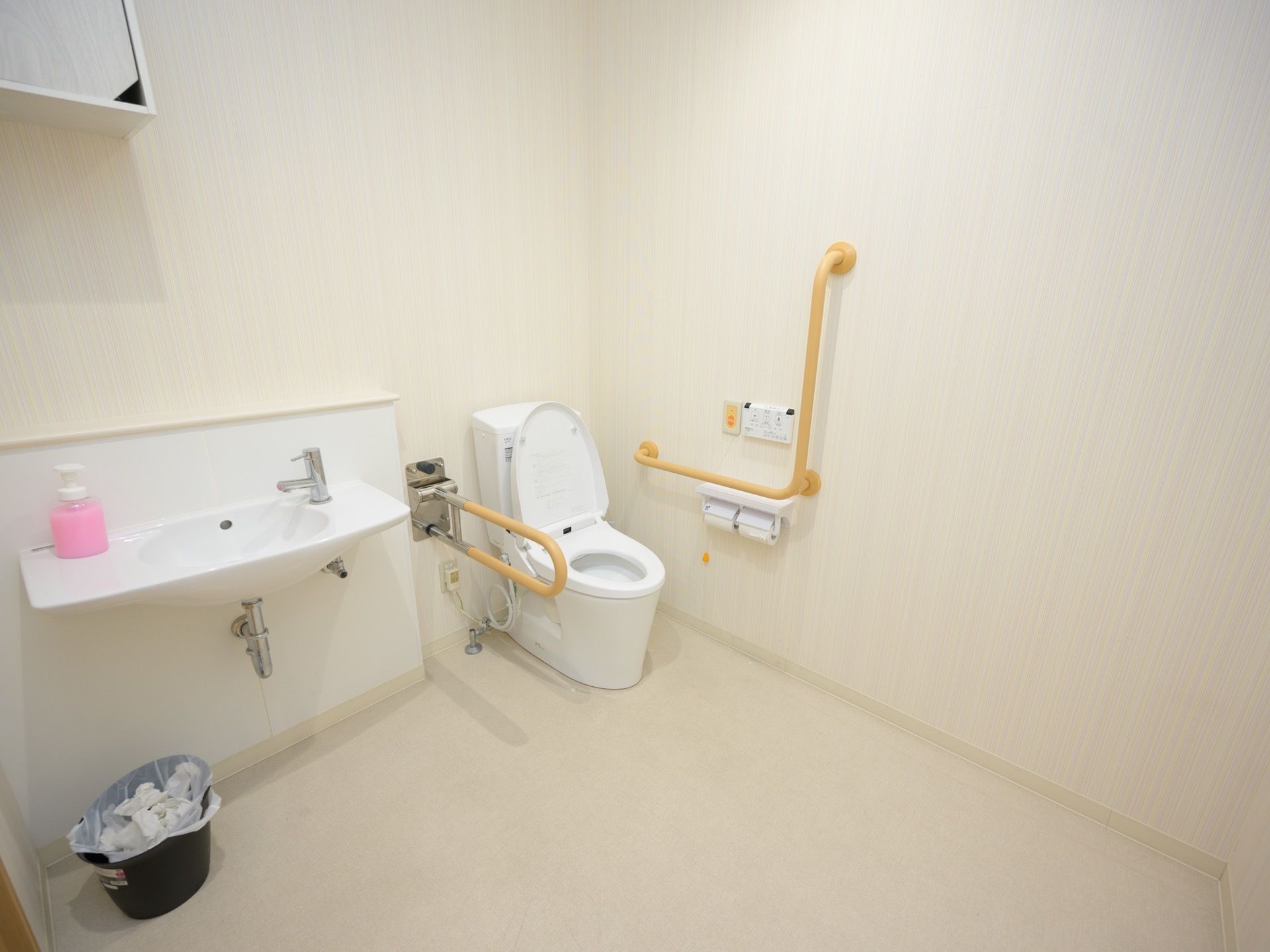 白を基調とした広々としたトイレである。手洗いスペースも併設されており、便利に使用できる。壁には緊急呼び出しボタンが備わっている。