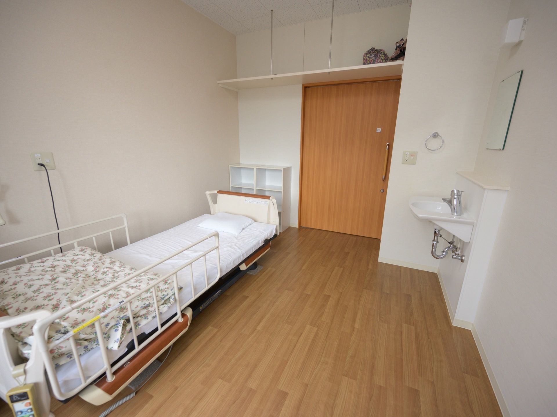 シンプルなワンルームの部屋である。介護用ベッドが用意されており、布団が置かれている。収納スペースがとられている