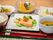 サーモンをメインとした食事。白いご飯や小鉢が並び、箸は箸置きに置かれている。