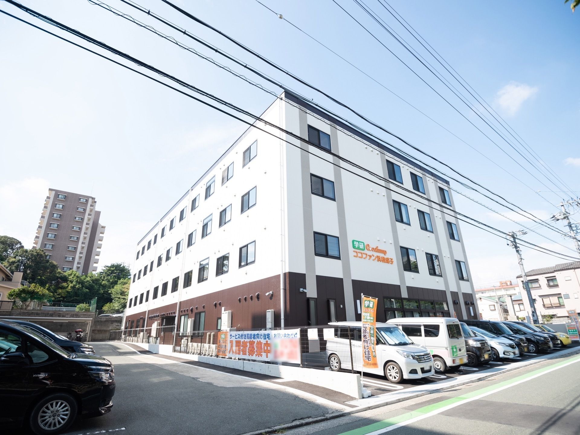 4回建ての建物で、1階の外壁は茶色で2階から4階の外壁は白色で塗装されている。道路に面した2回の外壁に施設名が書かれている。
