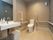 模様の入った壁紙が右手に貼られた個室トイレである。中央奥に温水洗浄便座が設置された洋式トイレがある。
