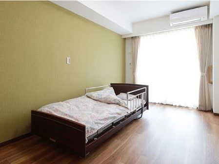 大きめの一人用ベッドとエアコンがある部屋。すぐそばにナースコールがある