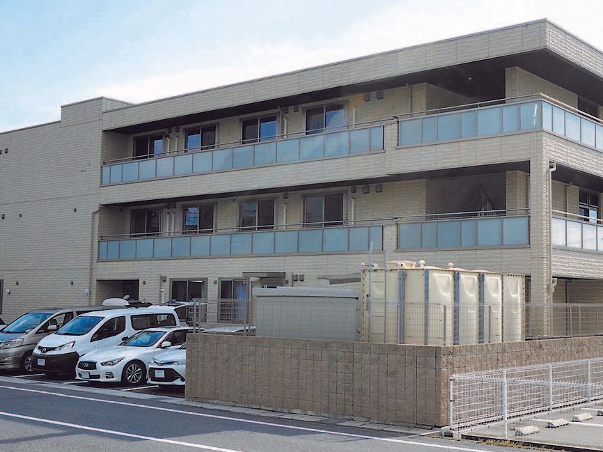 マンション風の鉄骨造の建物の様子。駐車場スペースがあるのが分かる