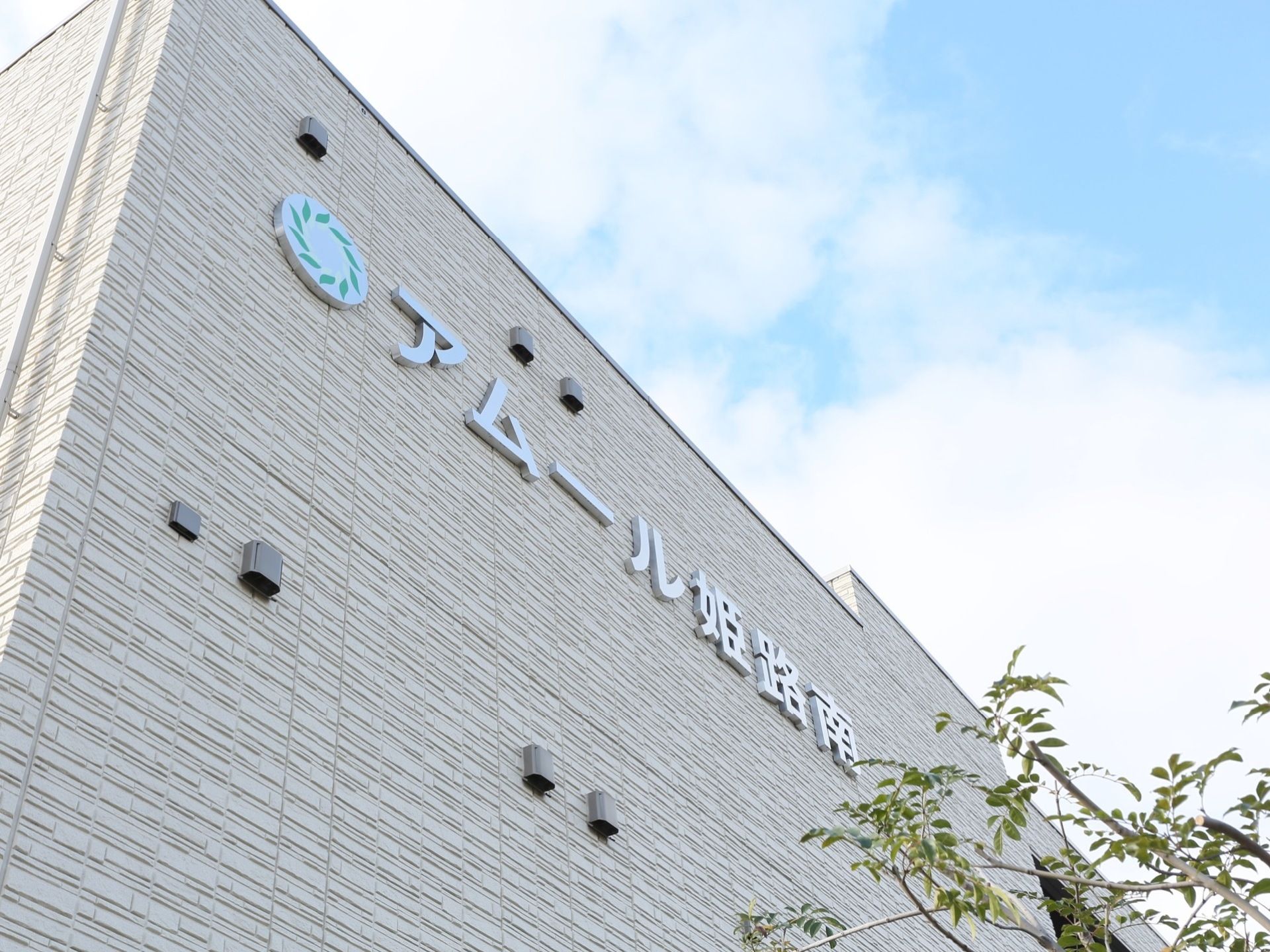 薄いグレーの外壁で、ところどころに排気口がついている。上層階の部分には大きく施設名が表示されている。