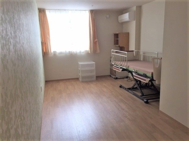 フローリングの居室にはベッドや収納家具を設置。すっきりとした明るいスペース。